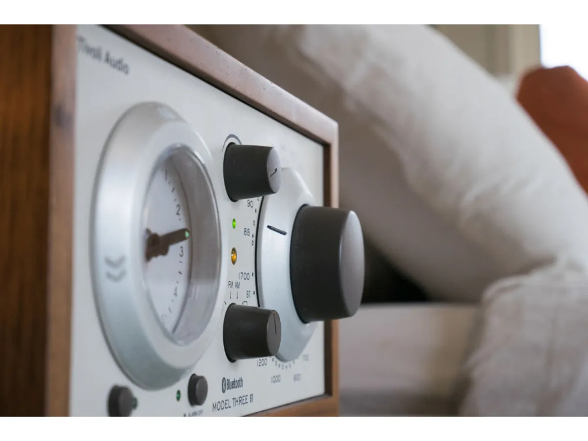 A close-up of a wooden-framed audio receiver with tactile dials, evoking nostalgia and the warmth of classic music listening. The scene suggests relaxing or entertaining guests with music, contributing to a welcoming and stylish atmosphere.